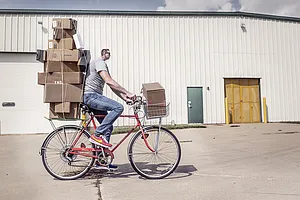 Man with small head, transporting parcels on his bike